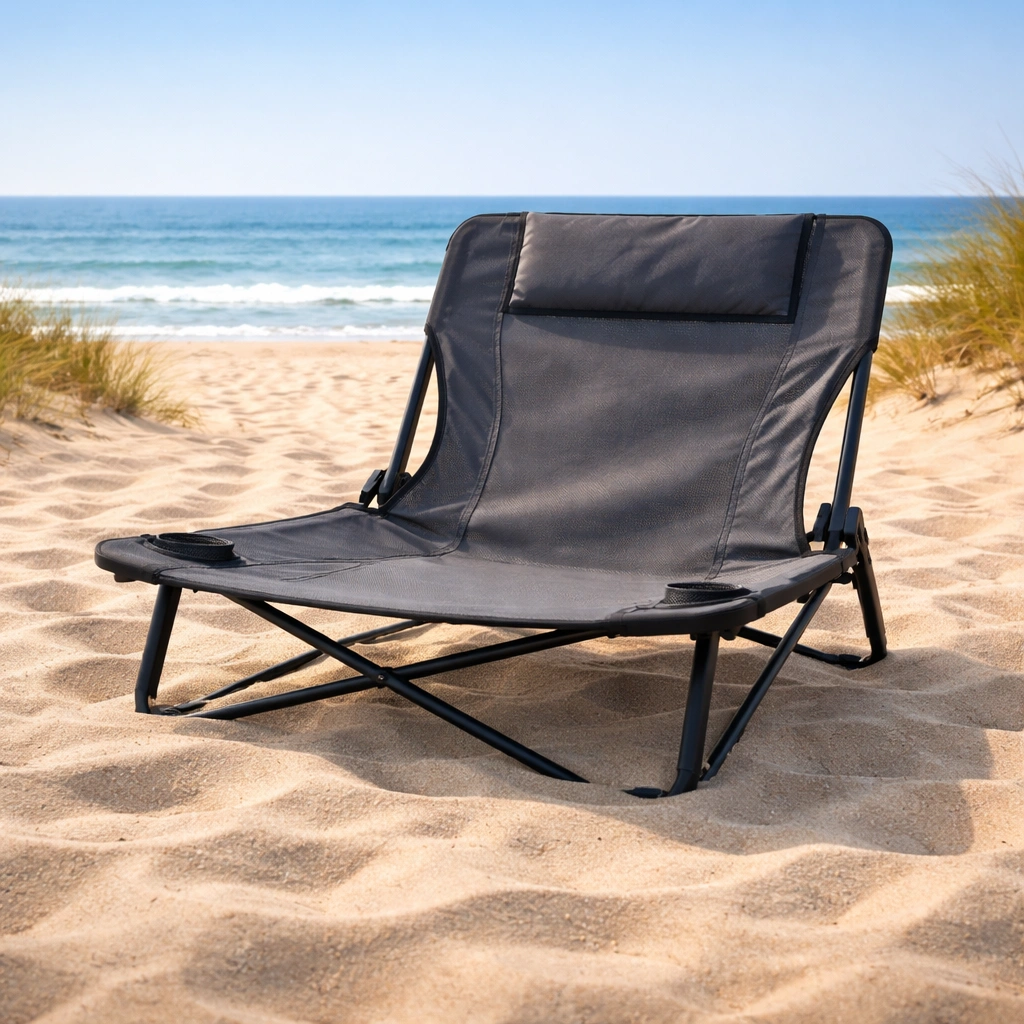 Low-profile beach chair sitting stable on soft sand dunes with ocean horizon in background