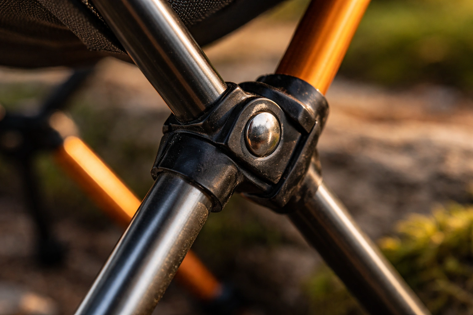Close-up of a camping chair hinge joint showing the pivot mechanism where two metal tubes connect