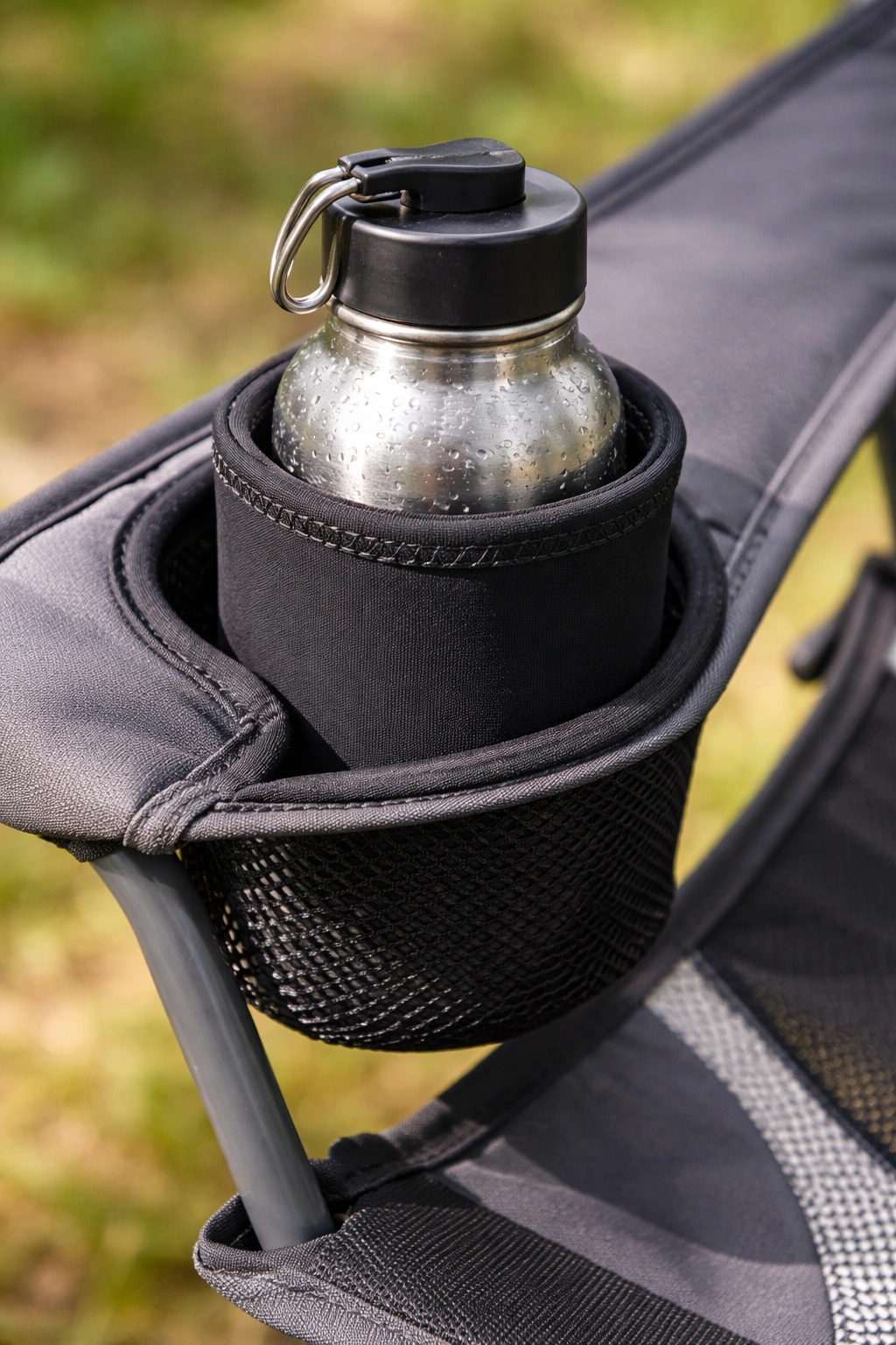 Close-up of black neoprene cup holder insert holding cold stainless steel water bottle with condensation in mesh holder