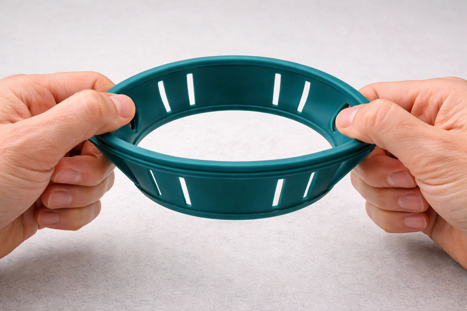 Person stretching teal silicone expandable cup holder insert to show adjustable fit flexibility