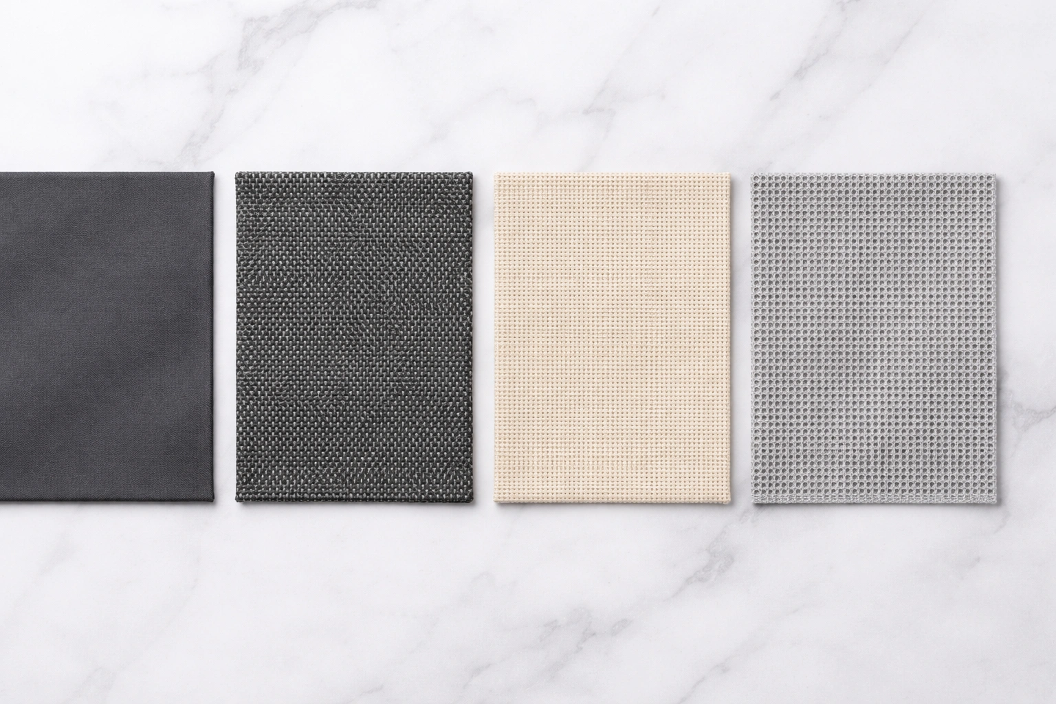 Four fabric swatches side by side on white marble surface showing 600D polyester 1200D polyester cotton canvas and mesh fabric