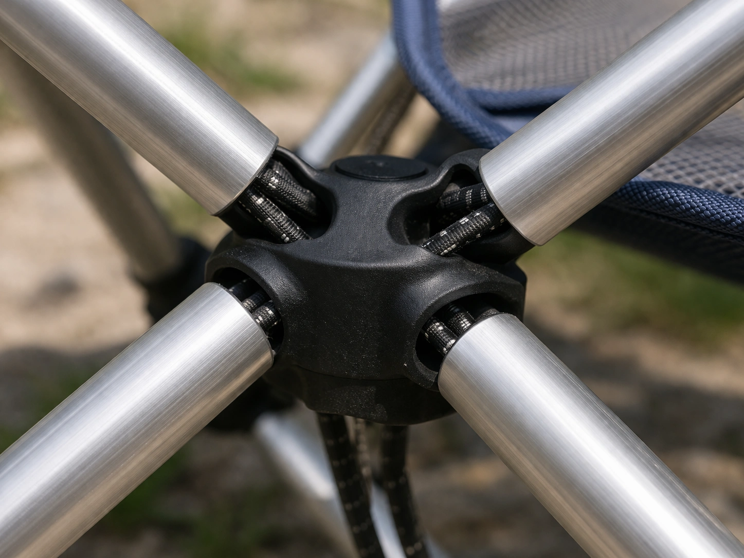 Macro detail of hub joint with shock-corded aluminum poles connecting to central plastic hub on pole-frame chair
