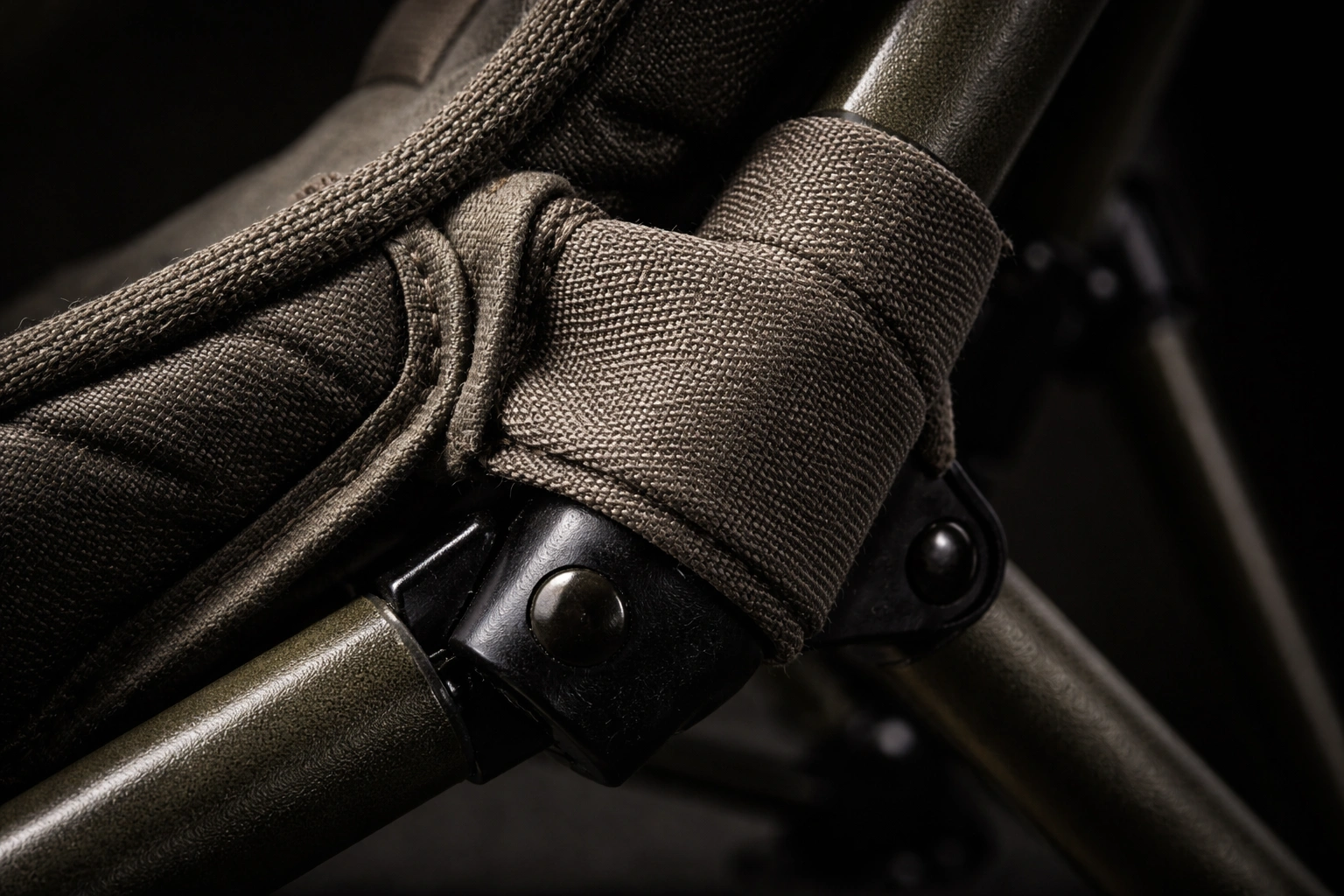 Close-up macro of fabric-wrapped silent hinge joint on dark olive chair frame