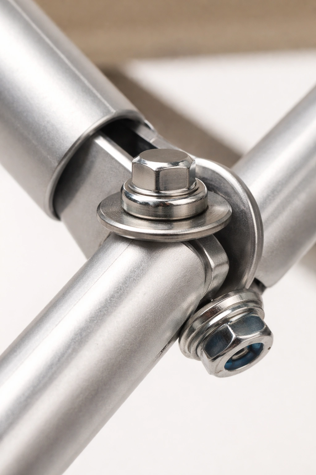 Close-up of stainless steel bolt with washer and lock nut replacing a rivet on a chair frame pivot joint
