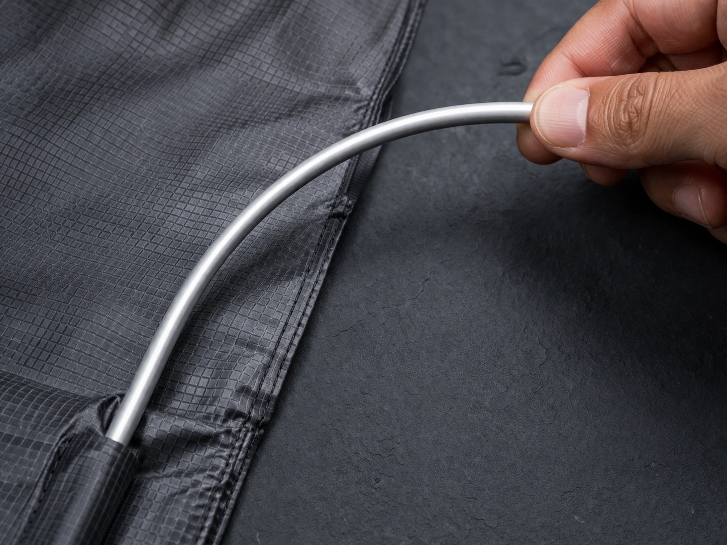 Close-up of aluminum alloy tent pole section and ripstop nylon fabric showing thin yet strong materials for ultralight chairs