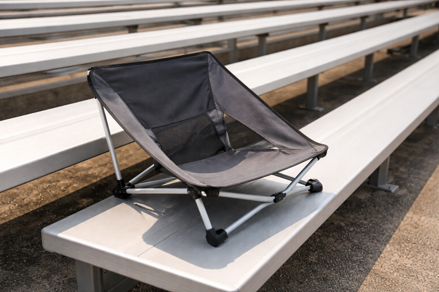 Low-profile compact chair on stadium bleacher steps showing it fits perfectly on bench surface