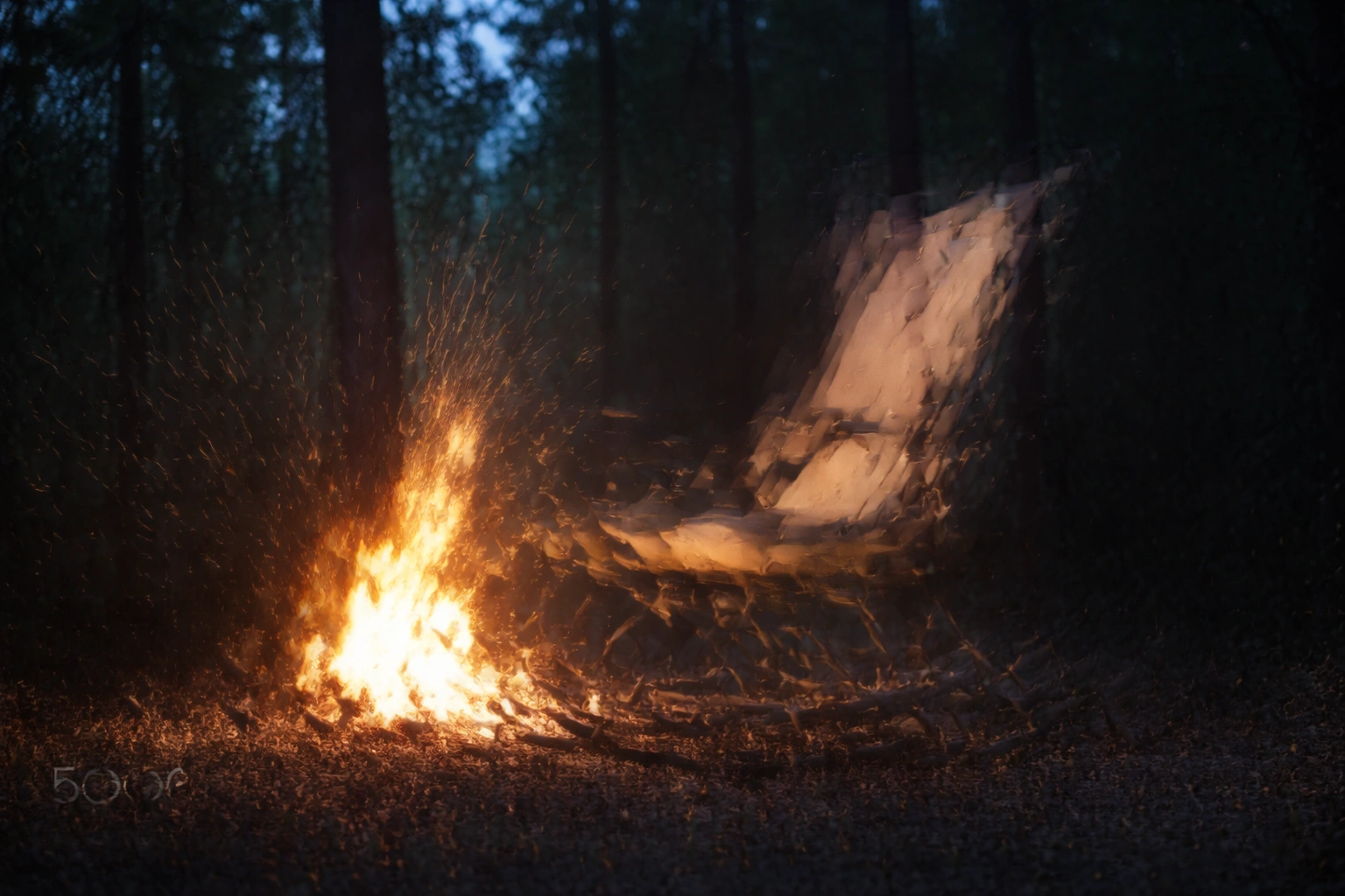 Rocking camping chair positioned near a warm campfire at twilight in a forest