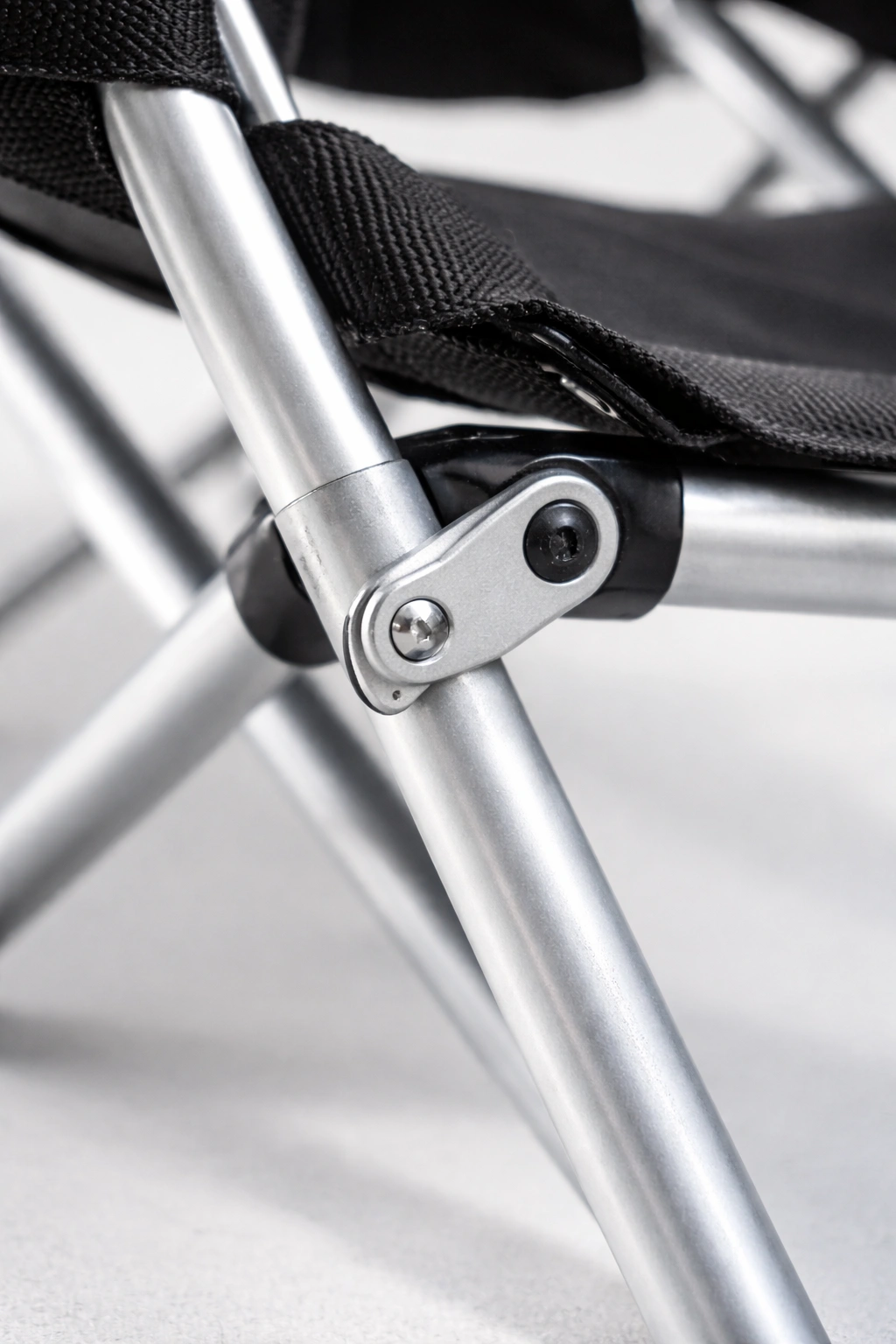 Close-up of slim aluminum camping chair frame tube with anodized finish showing foldable hinge joint mechanism